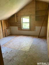 Bonus room featuring vaulted ceiling, wooden walls, and a textured ceiling