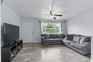 Living area with ceiling fan, light wood finished floors, and baseboards