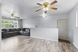 Living room featuring a ceiling fan, light wood-style floors, and baseboards