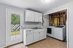 Washroom featuring washing machine and dryer, cabinet space, and a textured ceiling