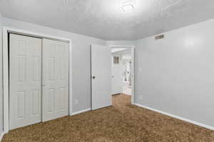 Unfurnished bedroom with carpet flooring, a closet, a textured ceiling, and baseboards
