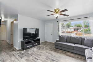 Living room with ceiling fan, baseboards, and light wood-style floors