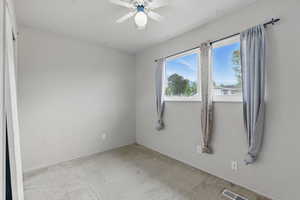 Empty room with ceiling fan, carpet floors, and baseboards