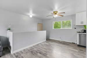 Kitchen featuring dishwasher, ceiling fan, light wood-type flooring, and white cabinetry