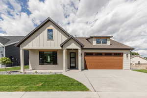 Modern farmhouse style home featuring concrete driveway, a front yard, a garage, and a shingled roof