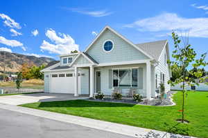 View of front of house featuring a front yard, a shingled roof, and driveway