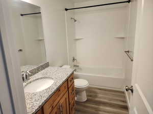 Bathroom featuring wood finished floors, toilet, vanity, and bathtub / shower combination