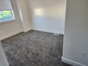 Spare room featuring dark carpet and baseboards