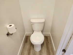 Bathroom with wood finished floors, toilet, and baseboards