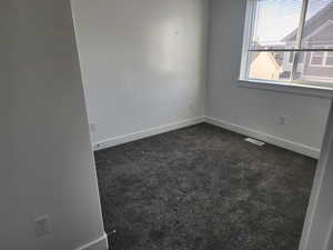 Unfurnished room with dark colored carpet and baseboards