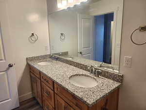 Bathroom featuring double vanity, wood finished floors, and baseboards