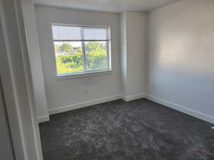 Empty room with dark carpet and baseboards
