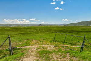 View of yard with a rural view, fence, and a mountain view