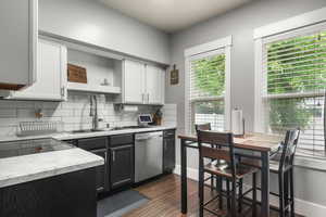 Kitchen featuring dishwasher, a sink, open shelves, and healthy amount of natural light