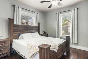Primary bedroom with dark wood-style floors and baseboards