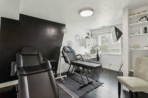 Office space with a textured ceiling, wood finished floors, and baseboards