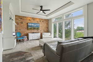 Living area with a raised ceiling, ceiling fan, and ornamental molding