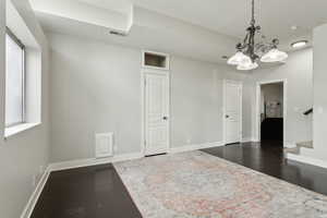 Spare room with dark wood-style floors, a chandelier, baseboards, and stairs