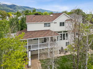 Back of property featuring a shingled roof, a patio, and a deck with mountain view