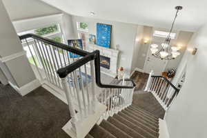 Stairway featuring baseboards, a glass covered fireplace, wood finished floors, and carpet