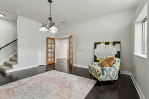 Living area with french doors, baseboards, stairs, dark wood-style floors, and a chandelier