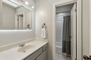 Bathroom featuring vanity, tile patterned floors, shower / bath combination with curtain, and a skylight