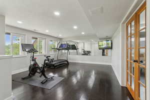 Exercise room with a textured ceiling, french doors, baseboards, wood finished floors, and recessed lighting