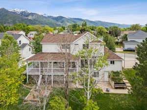 Back of property with a residential view, roof with shingles, a mountain view, and a patio area