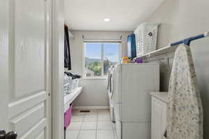 Laundry area with separate washer and dryer, baseboards, and light tile patterned floors