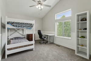 Carpeted bedroom featuring wainscoting, high vaulted ceiling, and ceiling fan
