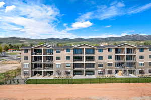 View of apartment building / complex featuring a mountain view and fence