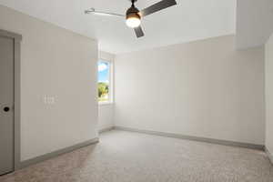 Carpeted empty room with a ceiling fan and baseboards