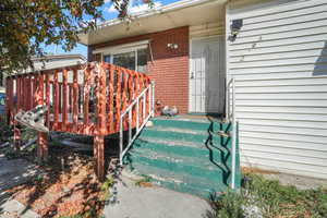 Property entrance featuring brick siding and a deck