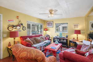 Living area featuring a ceiling fan, wood finished floors, and a textured ceiling