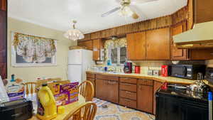 Kitchen featuring black appliances, exhaust hood, decorative backsplash, tile counters, and a sink