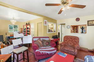 Living room with wood finished floors, ceiling fan, and a chandelier