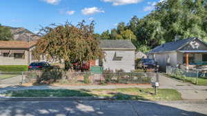 View of property hidden behind natural elements featuring a fenced front yard and concrete driveway