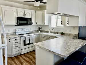 Kitchen with black microwave, white range with electric cooktop, a sink, a peninsula, and a ceiling fan