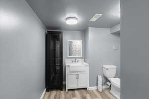 Bathroom with wood finished floors, toilet, vanity, and baseboards