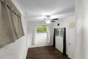 Hallway with dark wood finished floors and brick wall
