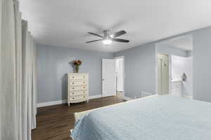 Bedroom featuring wood finished floors, baseboards, ensuite bathroom, and a ceiling fan