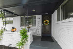 View of exterior entry with covered porch and brick siding