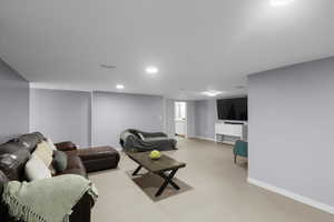 Living area featuring baseboards, light colored carpet, and recessed lighting