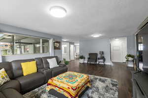 Living room with wood finished floors, a textured ceiling, and baseboards