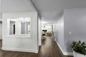Corridor with wood finished floors, baseboards, and a chandelier