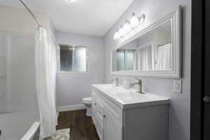 Bathroom featuring toilet, wood finished floors, vanity, and baseboards