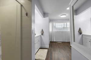 Ensuite bathroom with vanity, a shower stall, wood finished floors, and baseboards
