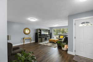 Living area featuring wood finished floors, baseboards, and a textured ceiling