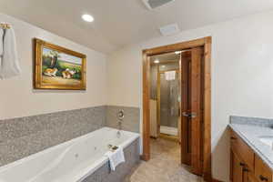 Full bathroom featuring a stall shower, a jetted tub, tile patterned flooring, vanity, and recessed lighting