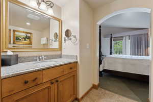 Bathroom featuring baseboards, tile patterned floors, vanity, and connected bathroom